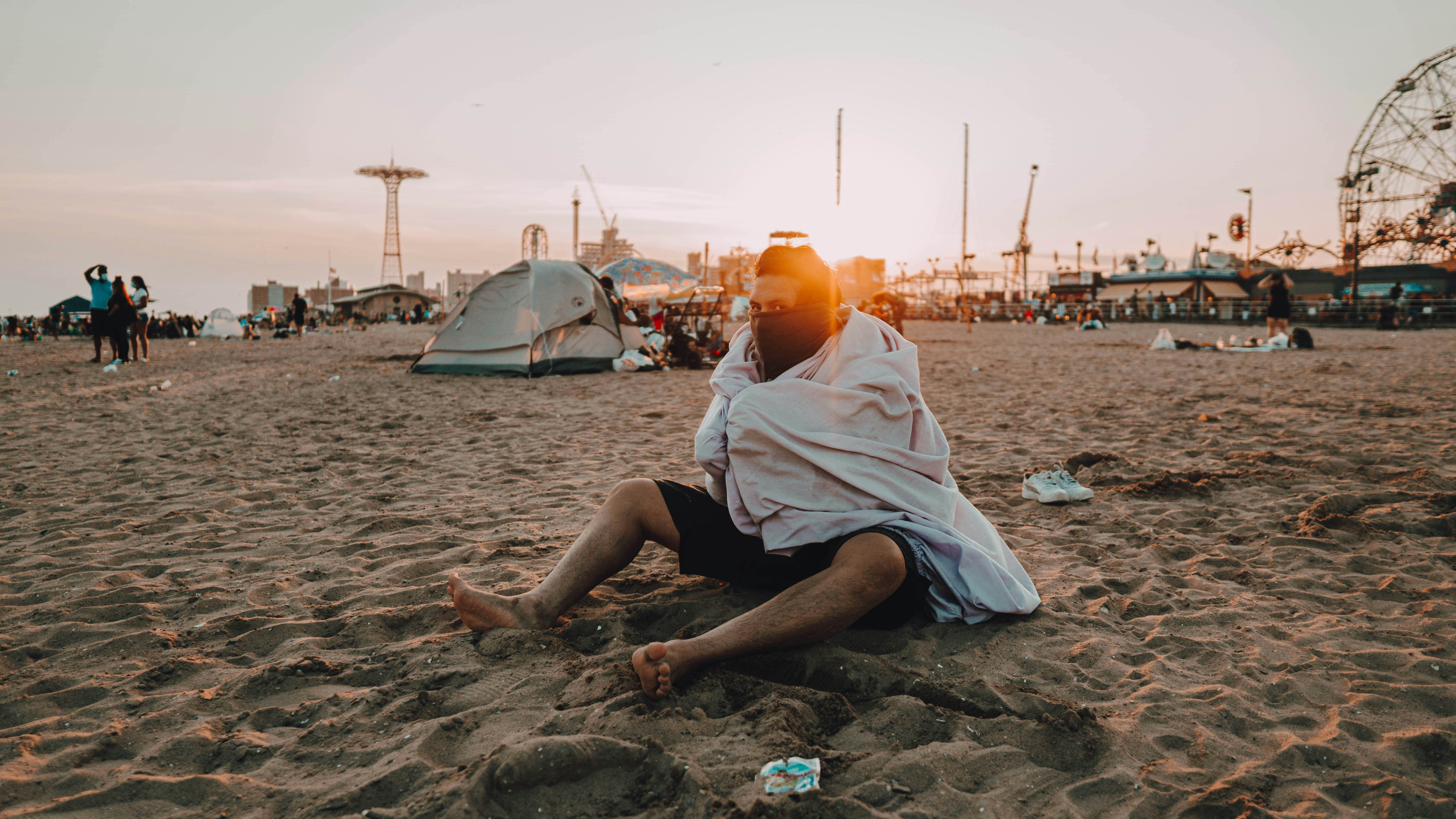 man in white towel sitting on beach during daytime